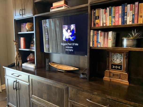 TV on wooden furniture next to books