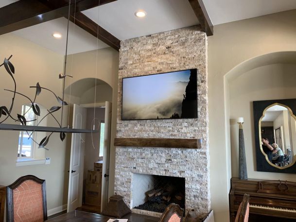 TV on stone wall above wooden mantle